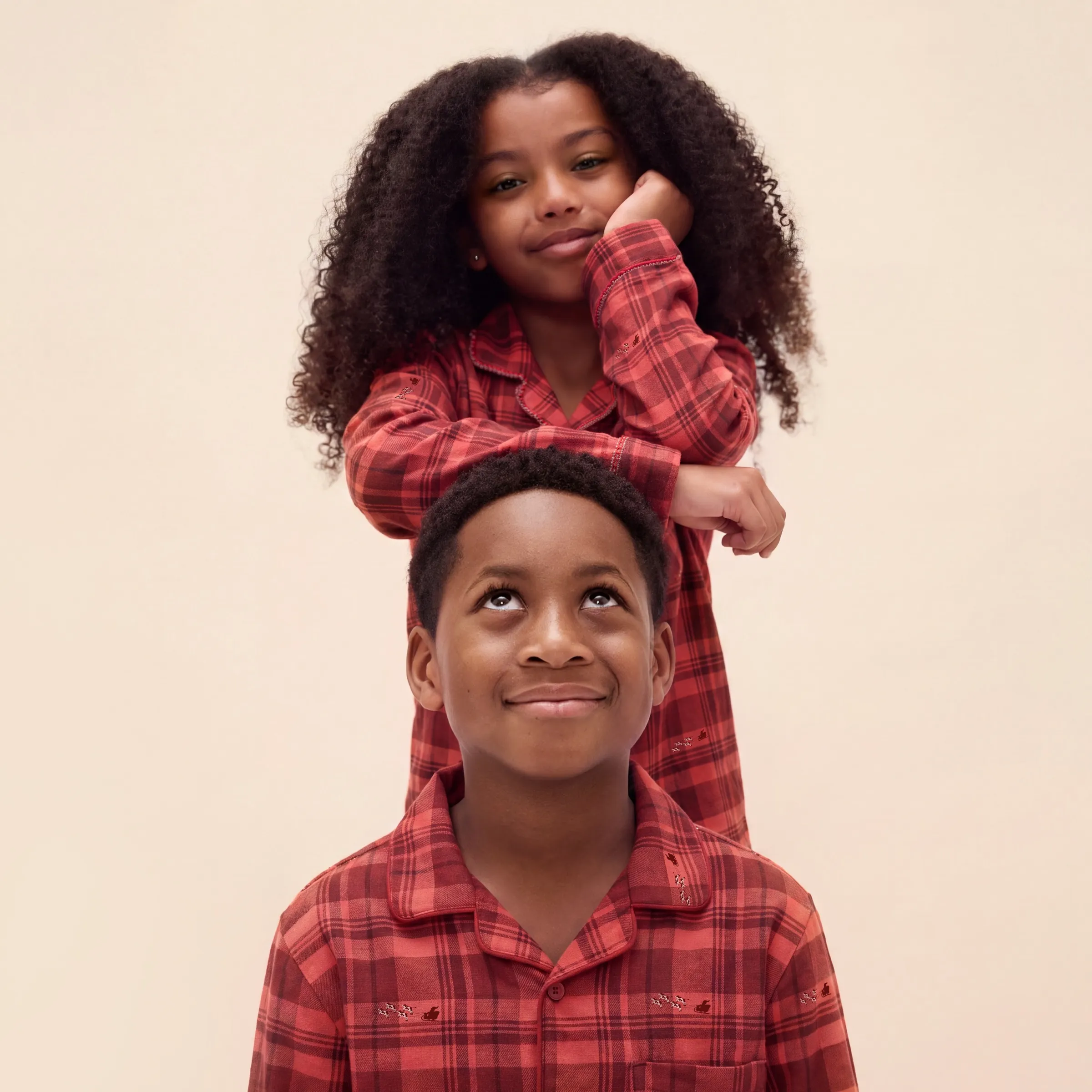 Brother and sister in red plaid Promised Land Dairy pajamas, her chin on his head