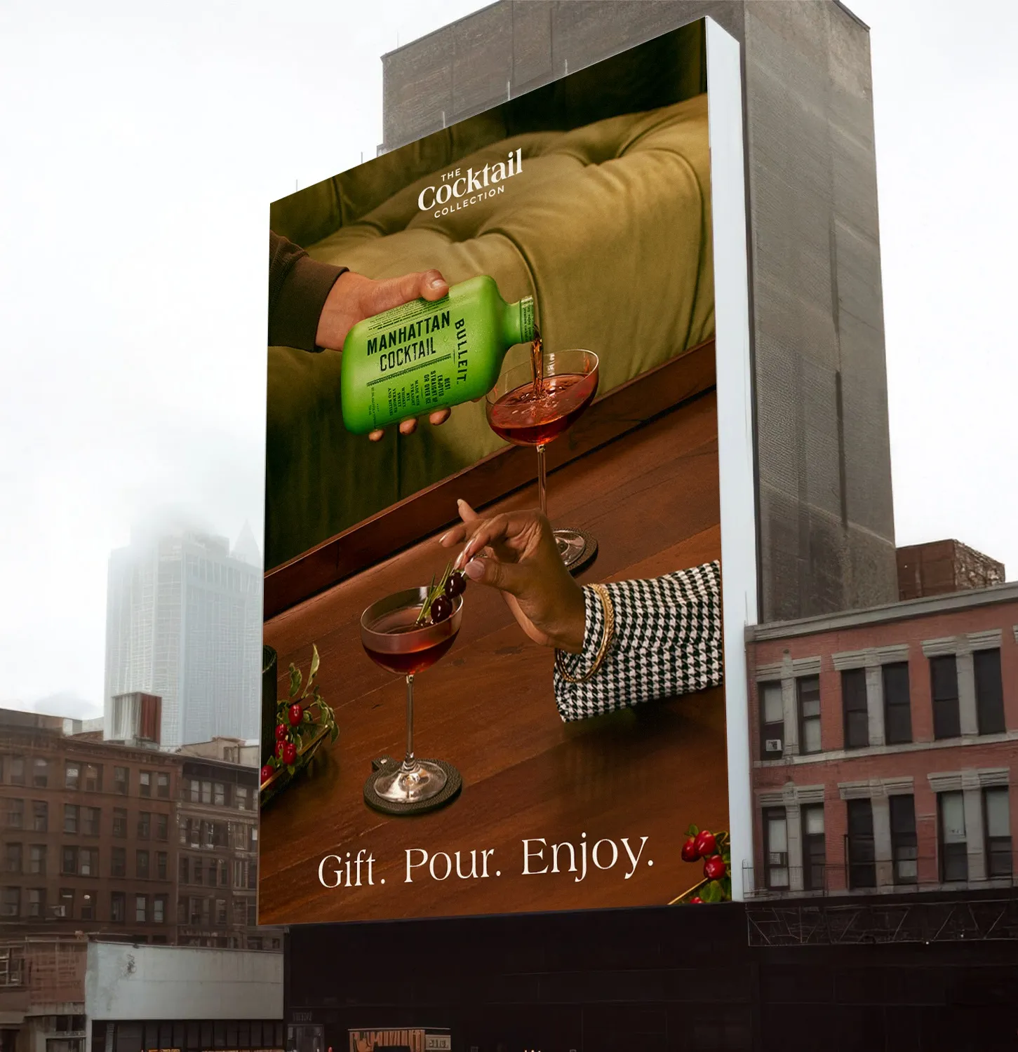 The "Gift. Pour. Enjoy." holiday billboard on a building: Bulleit Manhattan Cocktail poured into a coupe, The Cocktail Collection