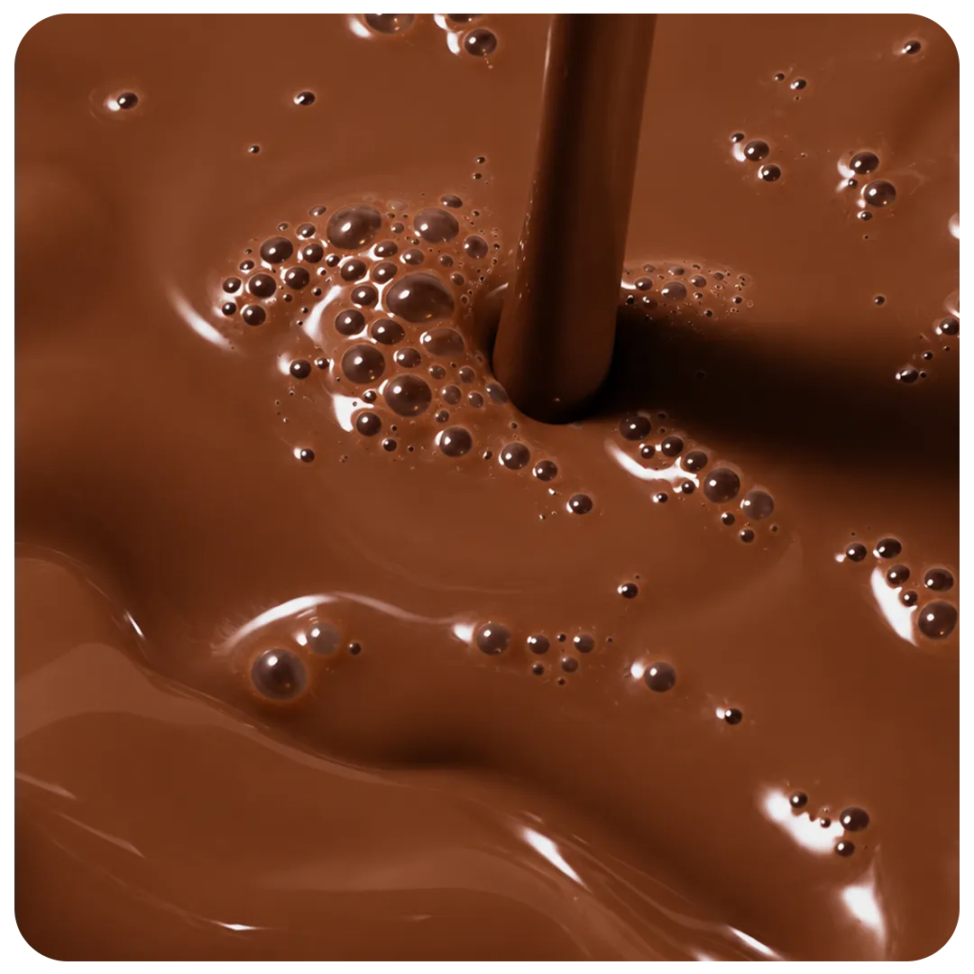 Macro shot of a stream of chocolate milk pouring into a glossy pool of it, bubbles scattered across the surface